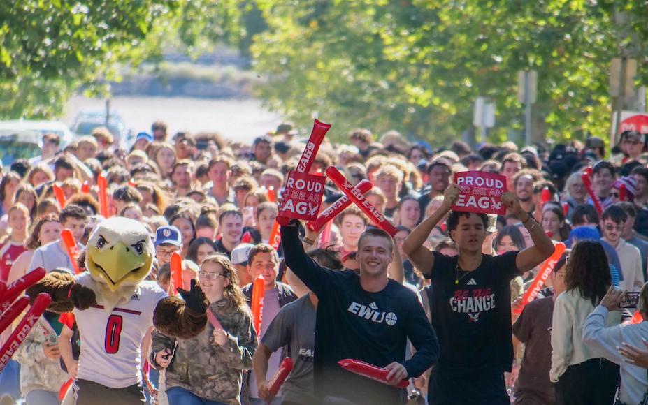 Crowd of students with Swoop as they pass through the pillars.