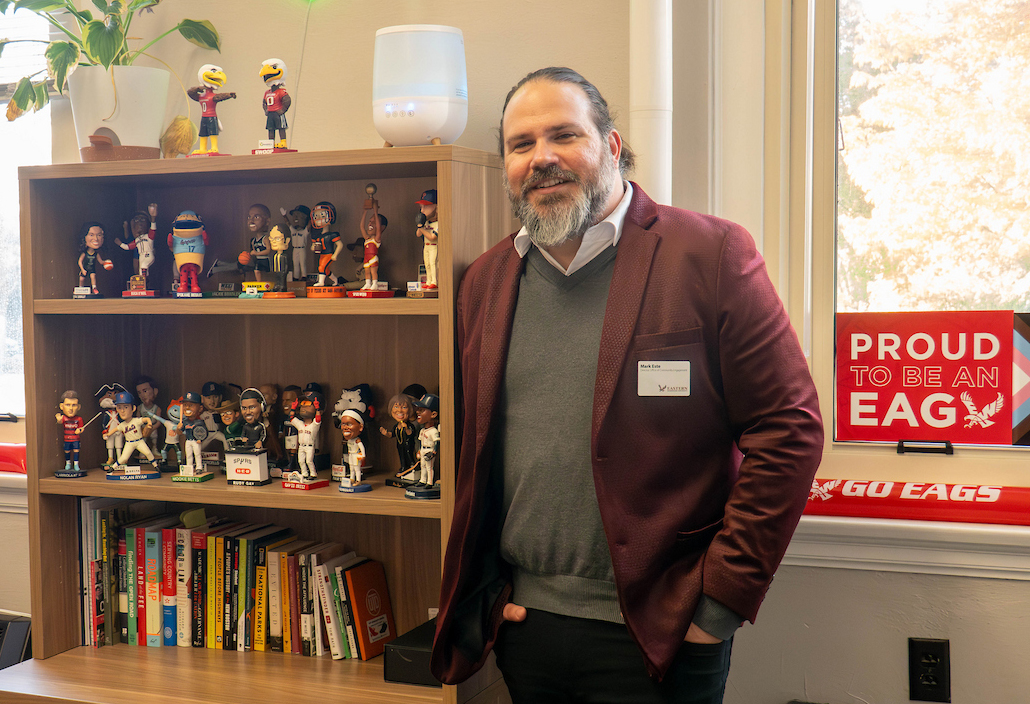Mark Este posed in front of his bobble head collection.