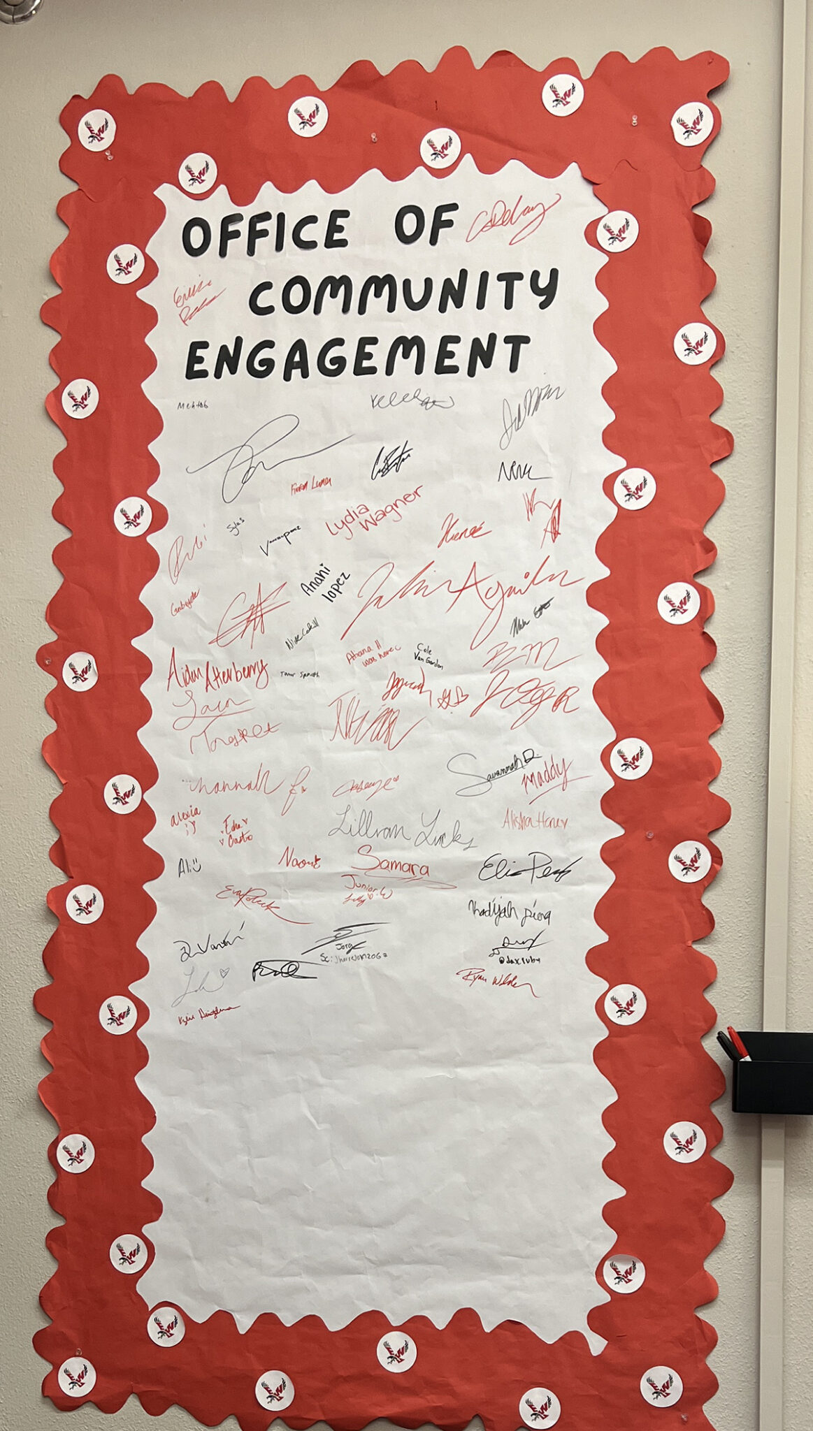 People signed a welcome poster on the wall.