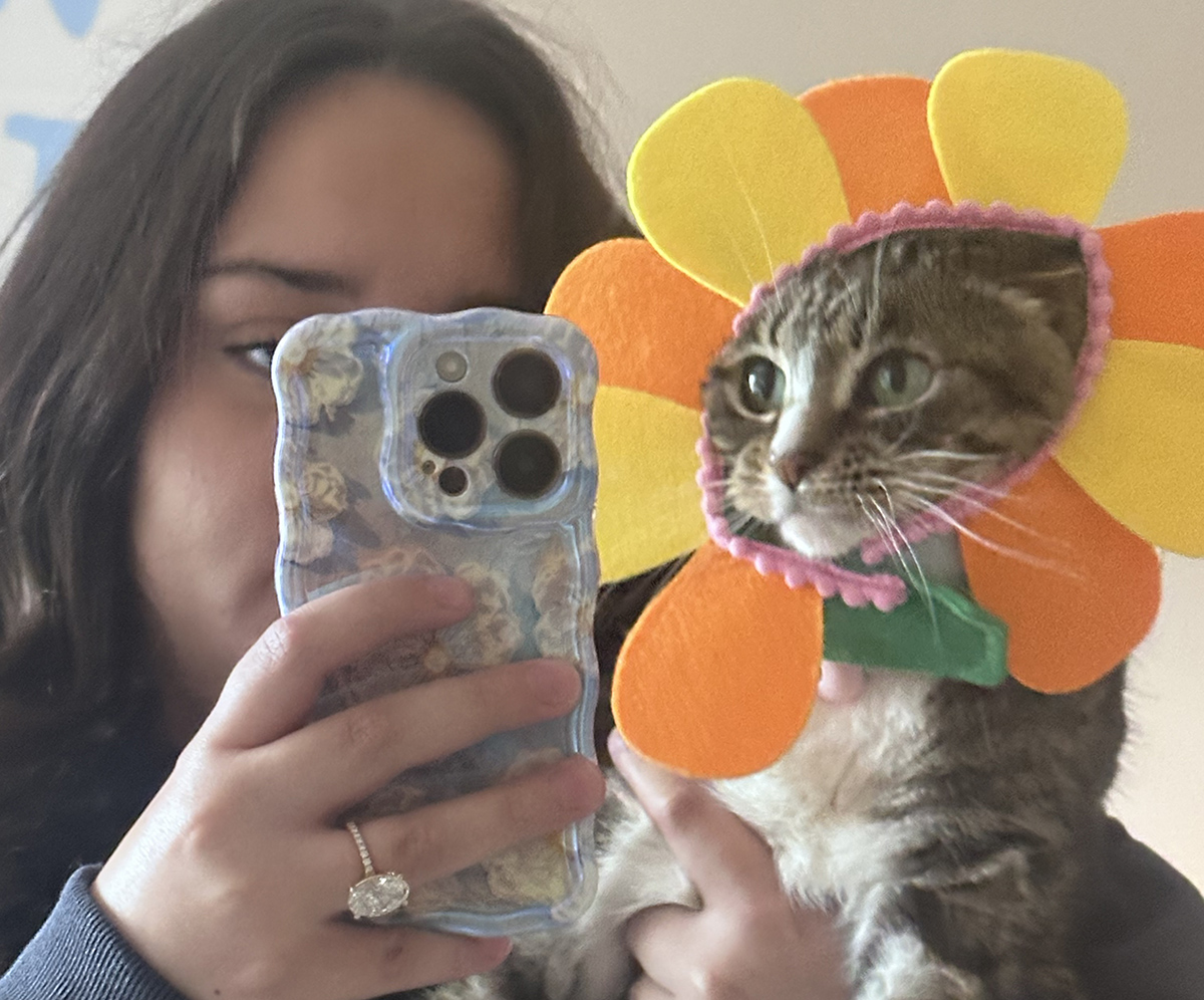 Photo of person taking a selfie with a cat in a flower costume.