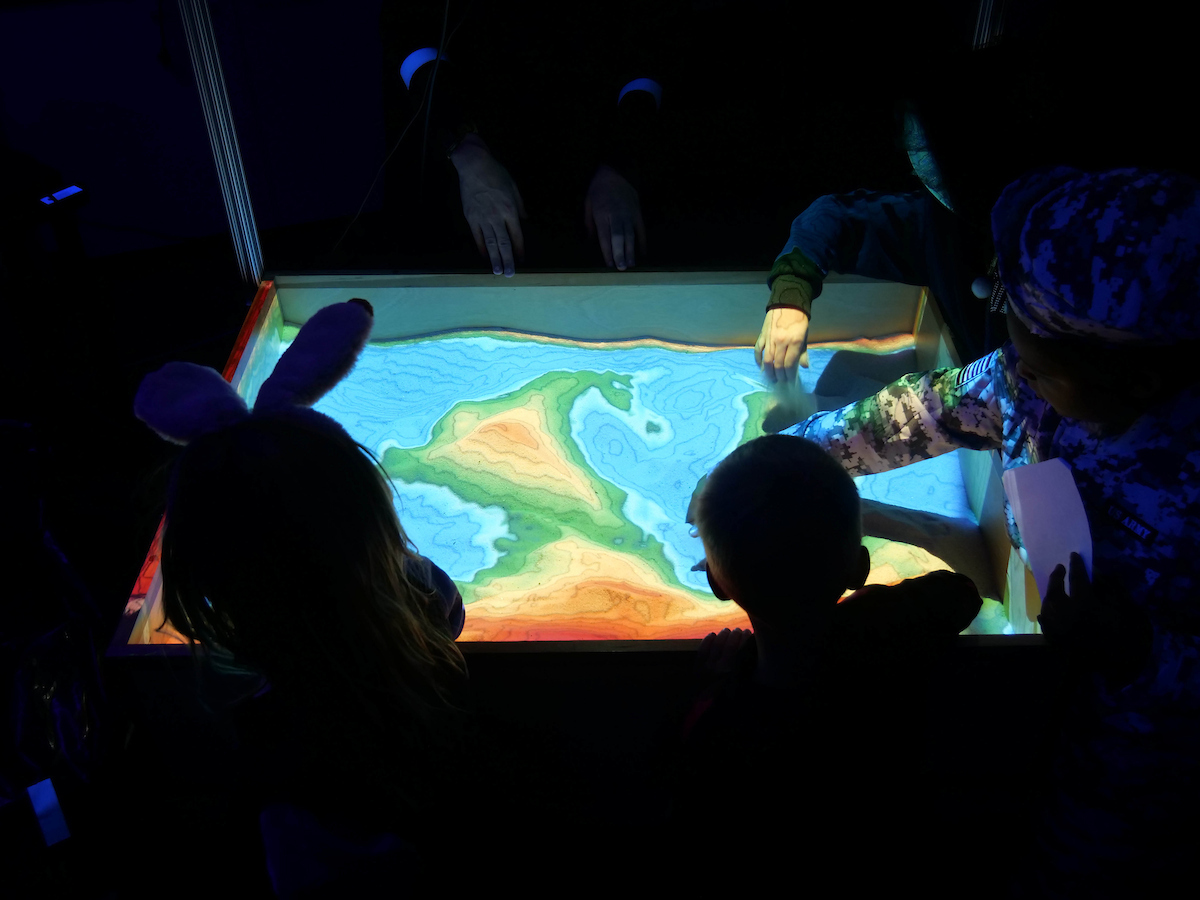 Illuminated topographic map with silhouettes of kids.