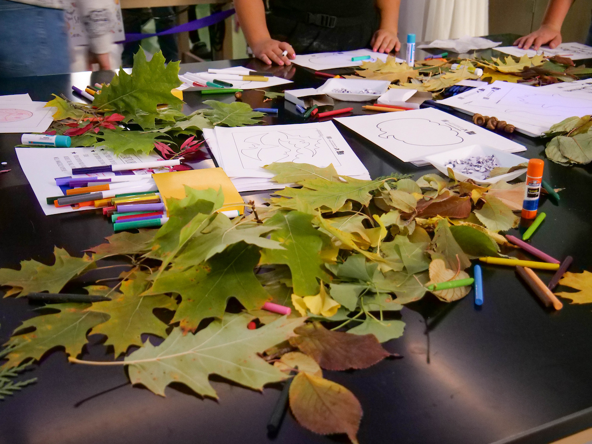 Table filled with leaves, paper and markers.