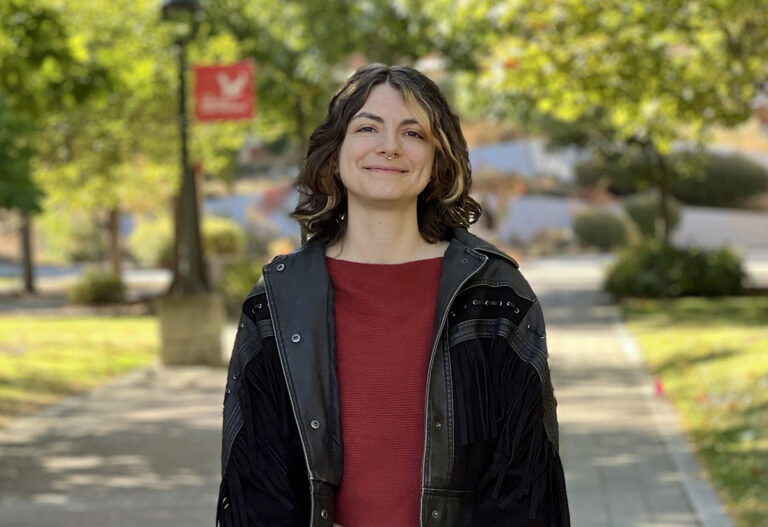 Xiola Sabastian on campus with an EWU flag in the background.