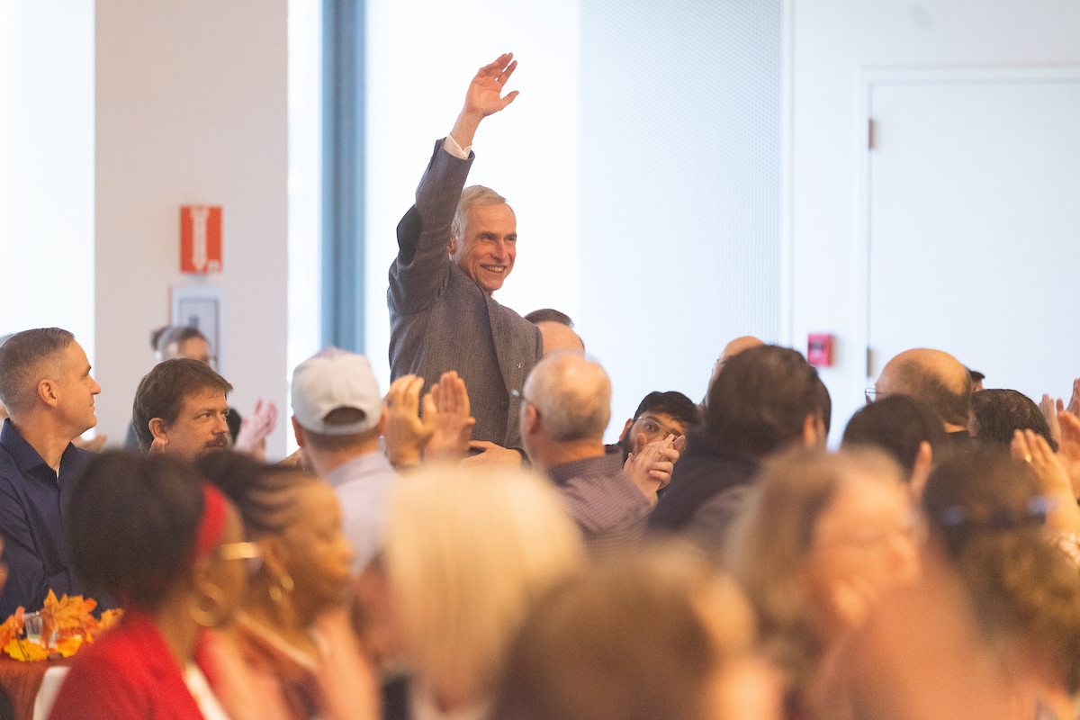 Professor raises his hand as people cheer for his 40 years of service.