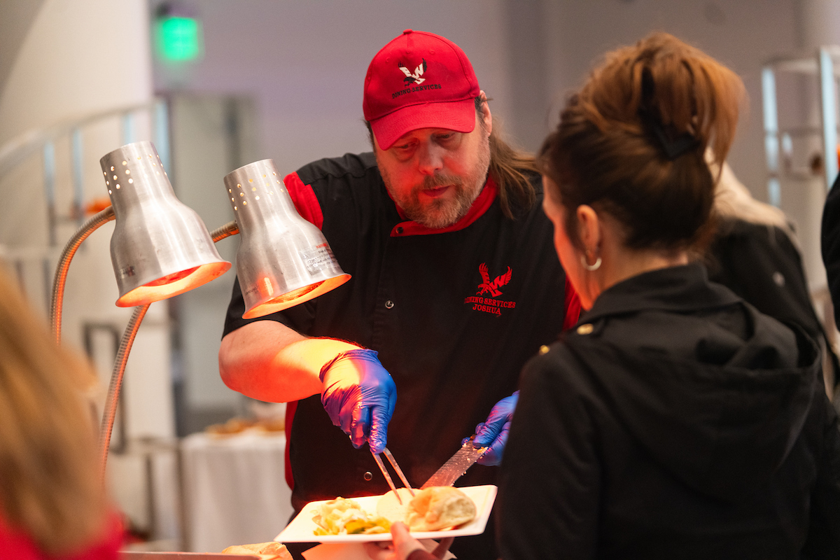 Catering chef carving turkey and serving it to employees.