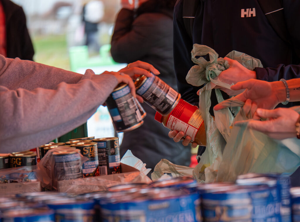 Photo of hands distributing canned goods.