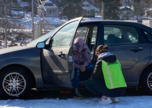 Volunteer talking with a homeless person sitting in his car.