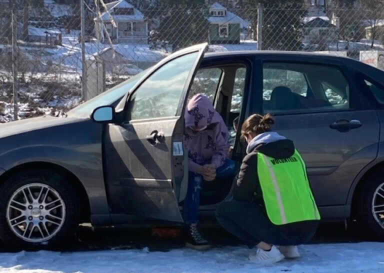Volunteer talking with a homeless person sitting in his car.