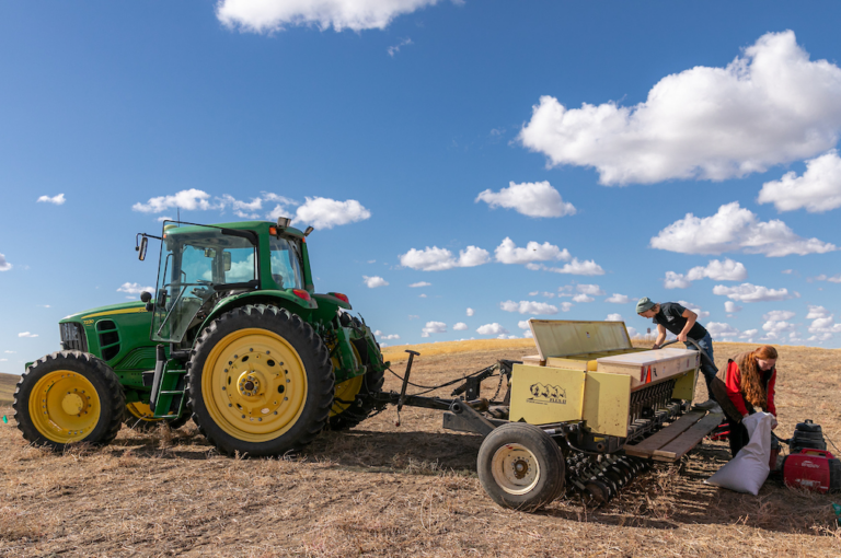 Tractor with students working with bags of seeds.