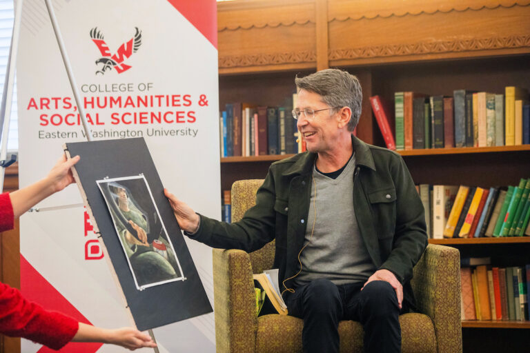 Jess Walter looking at a painting made by a student to illustrate a story of his.