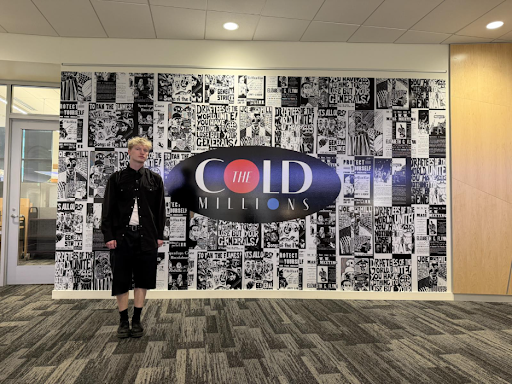Design student in front of large collage they designed for "The Cold Millions" exhibit at the library.