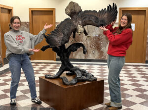 Hargreaves Eagle statue with two EWU student employees pointing to the eagle.