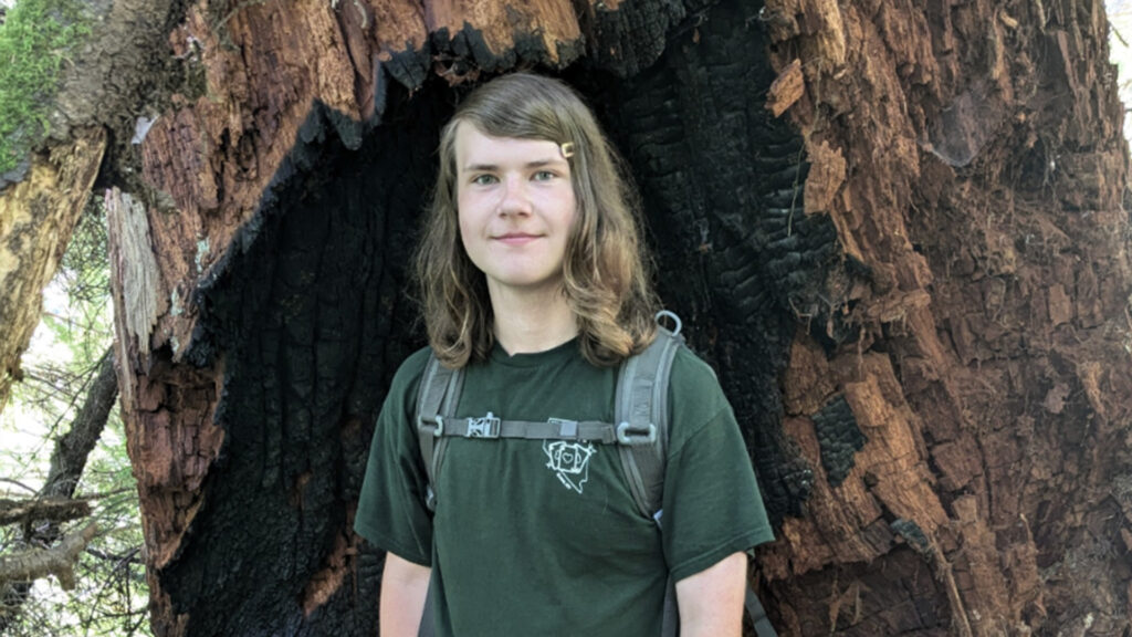 Photo of student who took second in the debate competition with a tree behind him.
