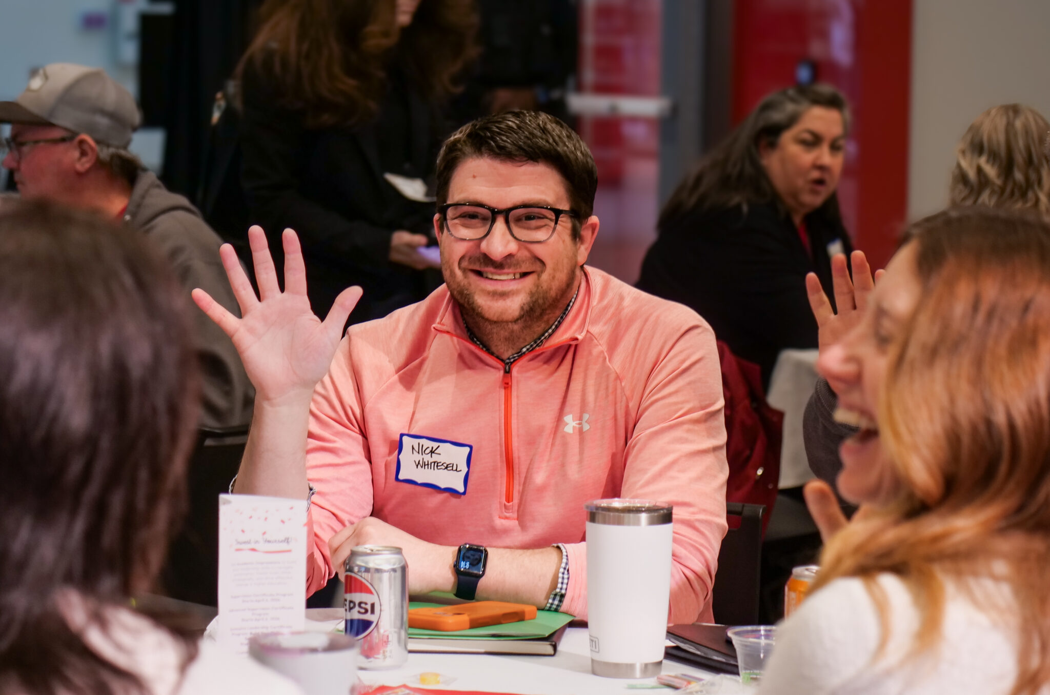 Employee smiling while holding up five fingers.