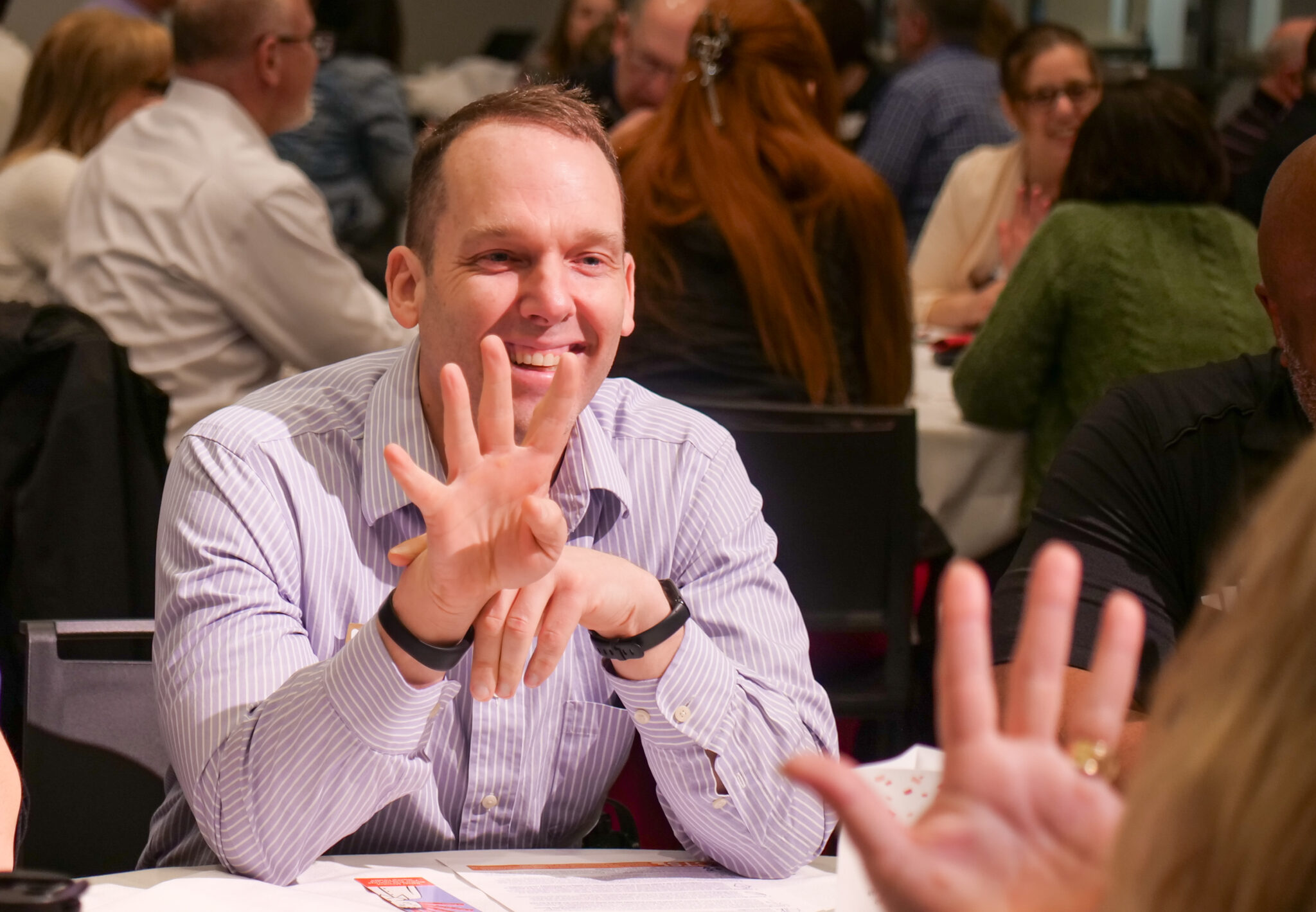 Employee smiling while playing the five-finger game with another coworker.