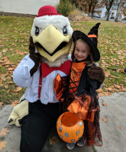 Zoë as a preschooler, dressed as a witch and standing next to Swoop.