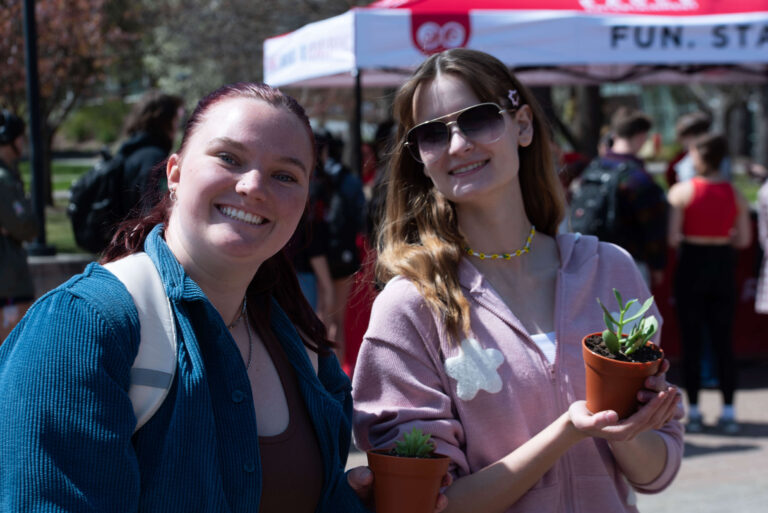 Two women hold two small plants.