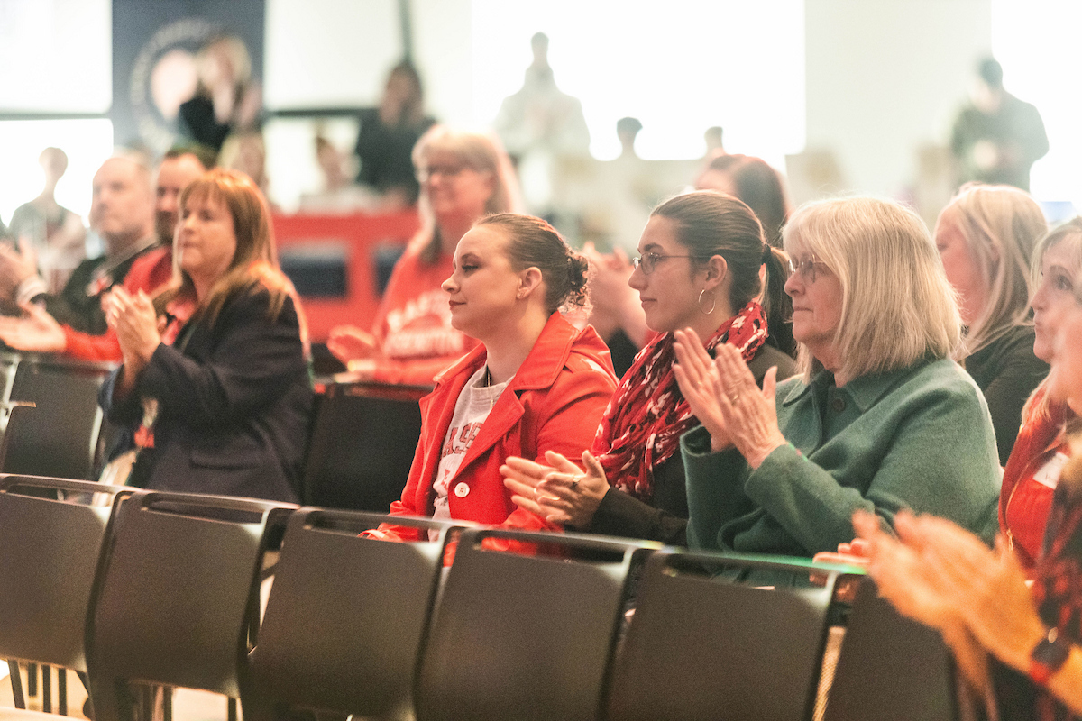 Faculty, staff and Bonnie Mager clapping.