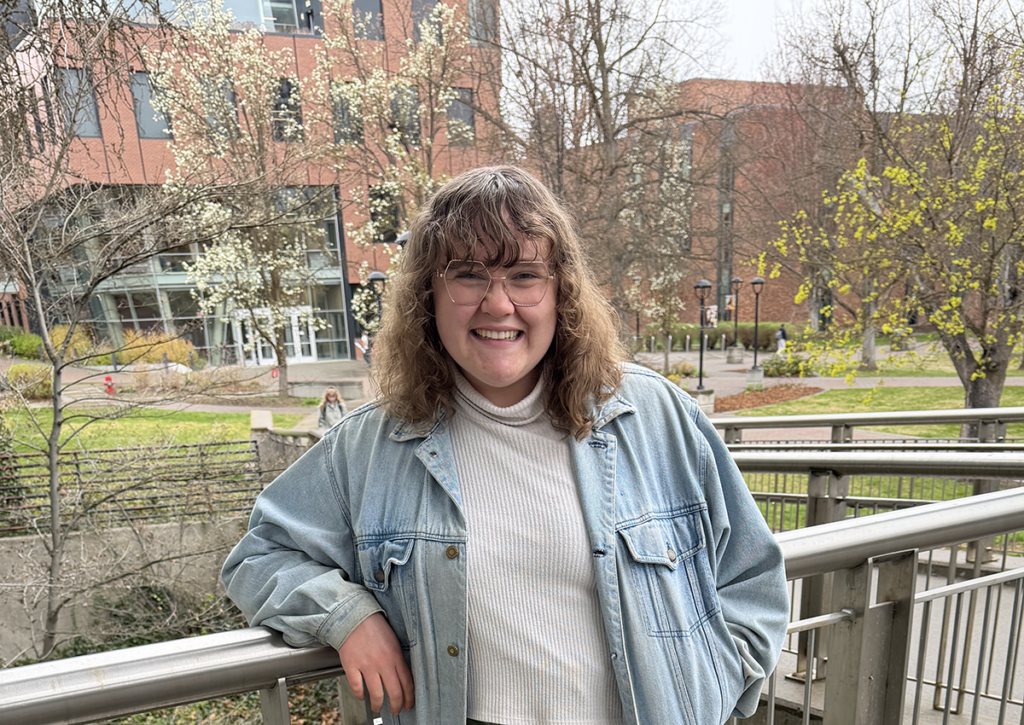 Emily on the steps of JFK with the ISC and some budding trees in the background.
