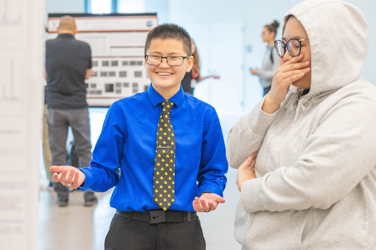 Student explaining poster presentation to another student