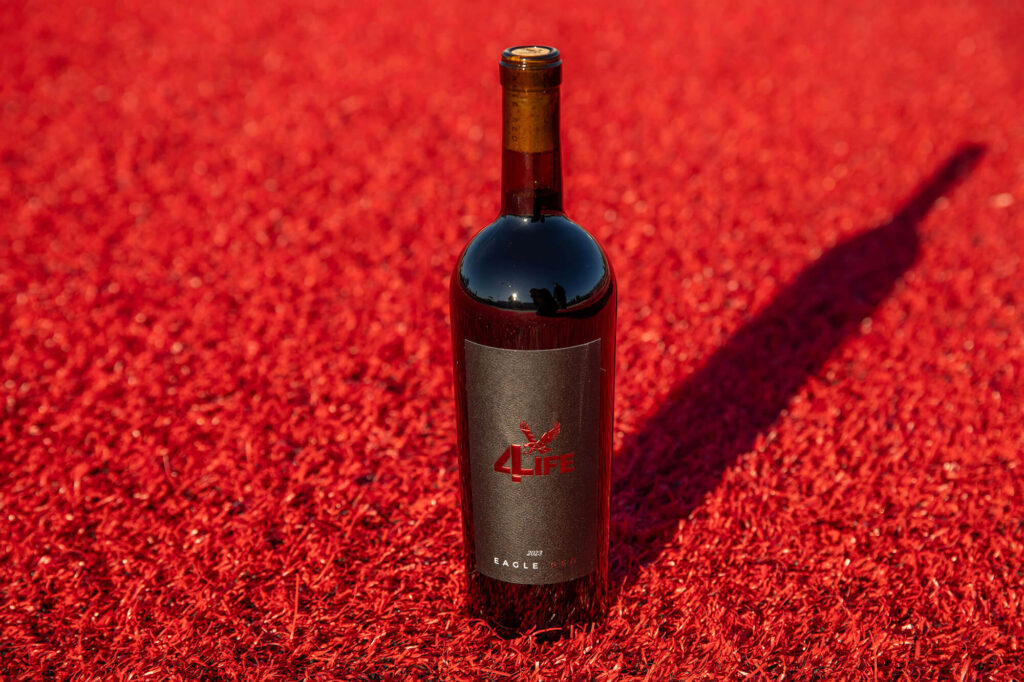 A bottle of Eagle Red wine on the red turf at Roos Field.