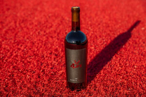 A bottle of Eagle Red wine on the red turf at Roos Field.