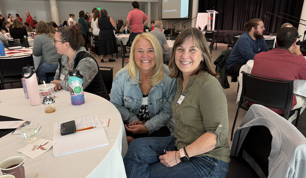 Two employees sitting at a table smiling.